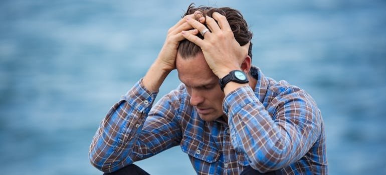 Man holding his heading while struggling with quitting drugs cold turkey.
