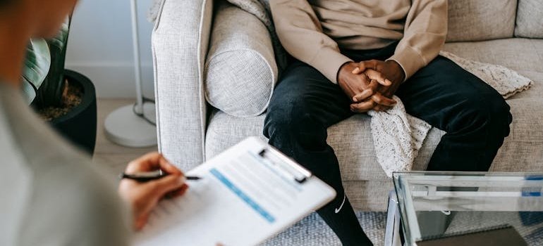 Woman writing in a clipboard while talking to a patient.