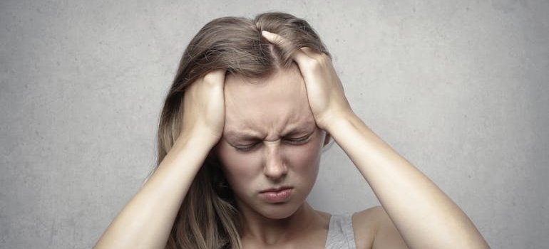 Woman holding her head while in pain.