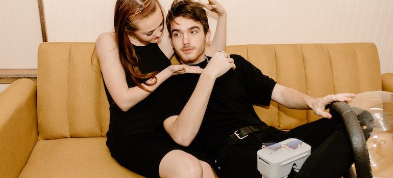 Woman and man on a couch in an uncomfortable hug which indicates codependency in addiction.