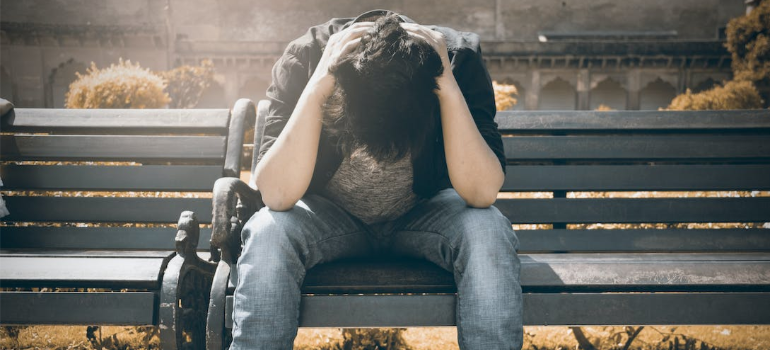 A depressed young man sitting on a bench.