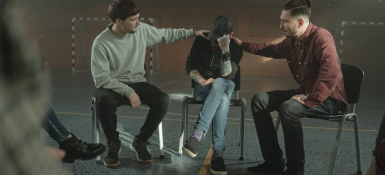 Two men consoling another during group therapy.