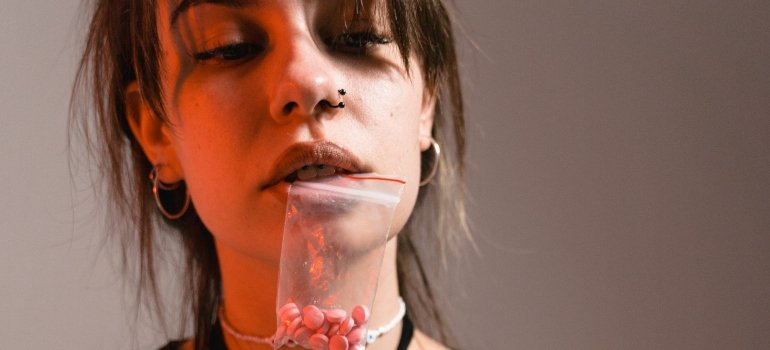 person holding a packet of drugs in their mouth