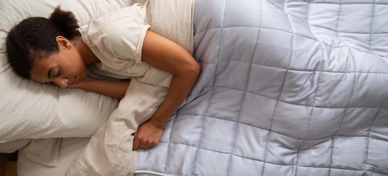 a woman sleeping under covers representing Does CBD play a role in addiction recovery?
