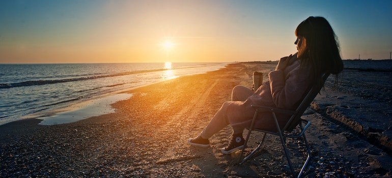a person in a chair at the beach at sunset