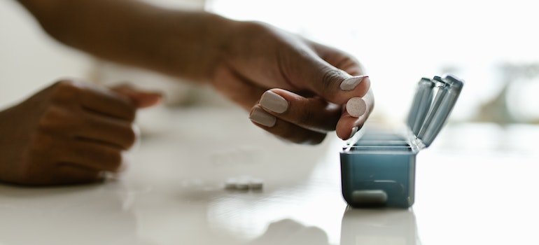 Person putting a pill in a medicine organizer.