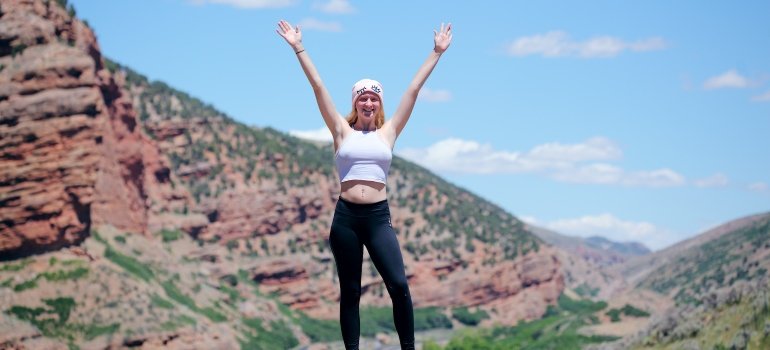 Confident woman standing on a cliff to symbolize boost in self-esteem as one of the lesser known benefits of addiction recovery
