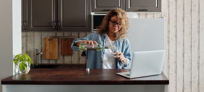 a woman pouring wine at a kitchen counter