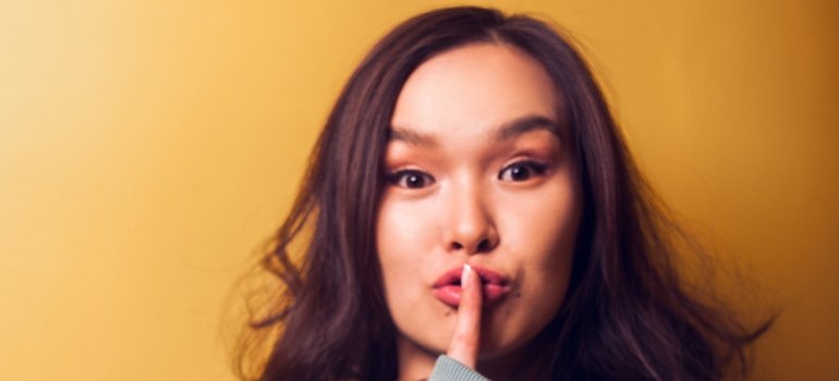 person with a finger on their lips, indicating confidentiality