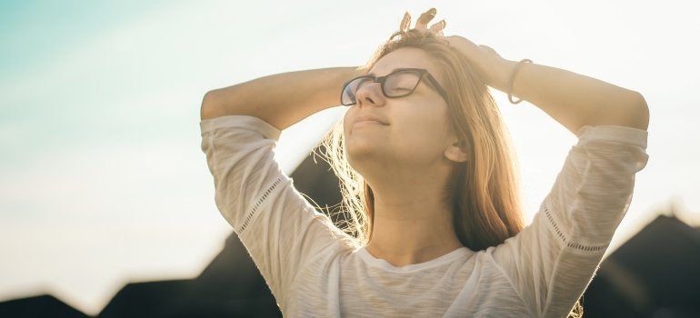 Woman looking happy holding her hands on her head and looking at the sky
