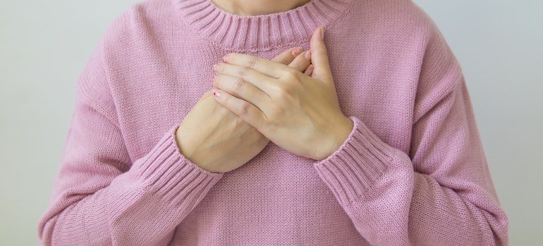 Person holding their hands over the chest.