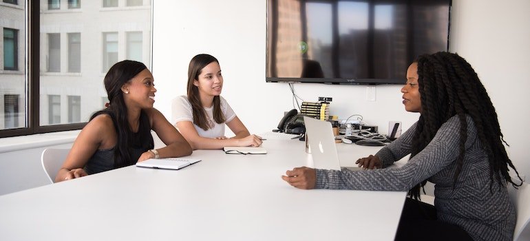 three women in an office talking to each other