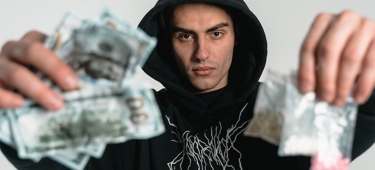 Cocaine, one of the deadliest drugs in Pennsylvania, is known for its stimulating effects. Man holding money in one hand and money in the other.