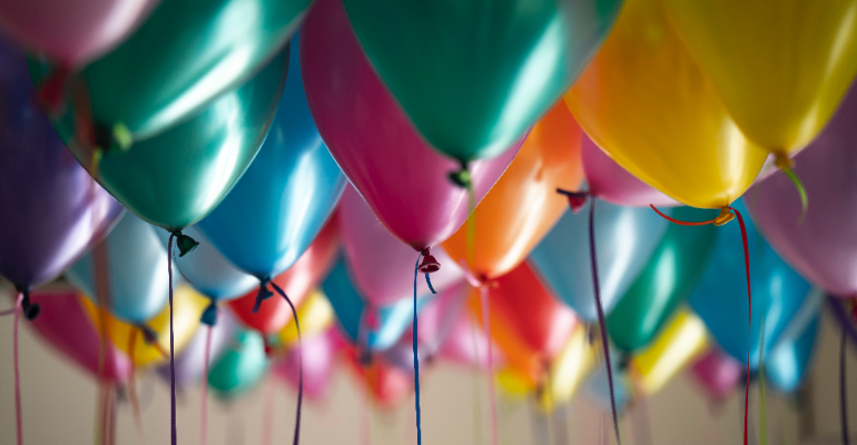 A bunch of helium balloons on a ceiling.