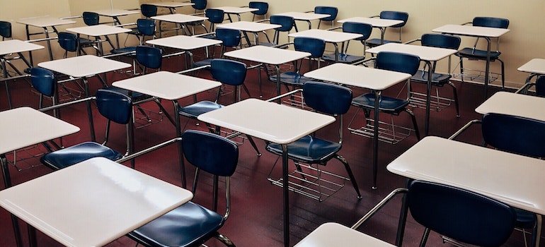 An old classroom with desks and blue chairs.