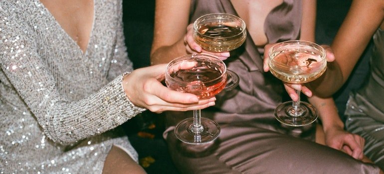 Close-up of a group of people holding alcoholic drinks at a party.