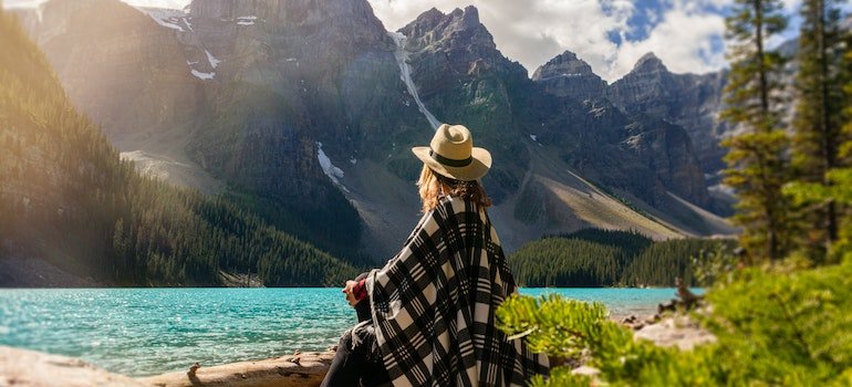 a woman with a hat standing in front of a lake
