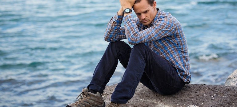 man sitting on a rock on a shore 