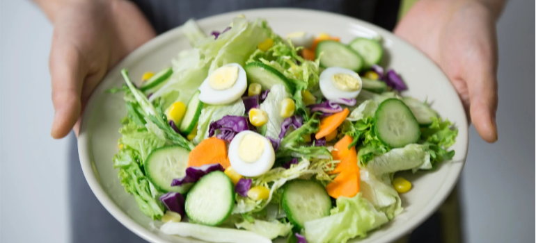 A person holding a salad bowl, showing how building a supportive sober social cycle in Pennsylvania is possible through proper nutrition.