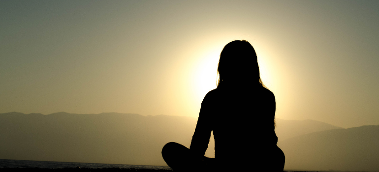 a girl looking at the sunset and being in peace