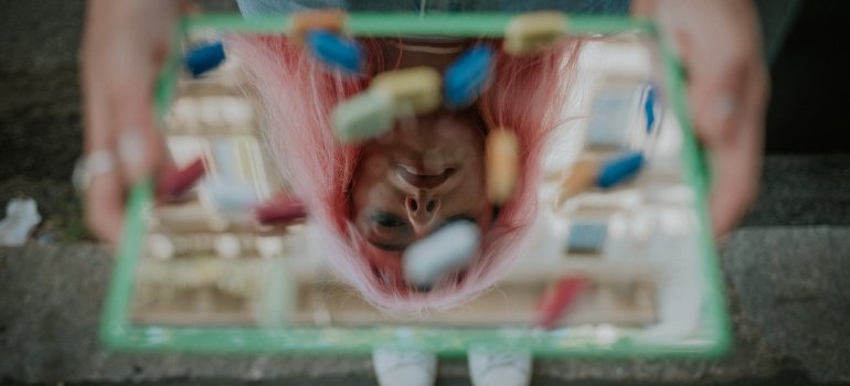 Picture of a person who is holding a mirror full of pills 