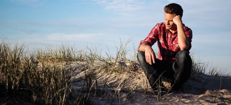 man sitting on the ground with his hand on his face