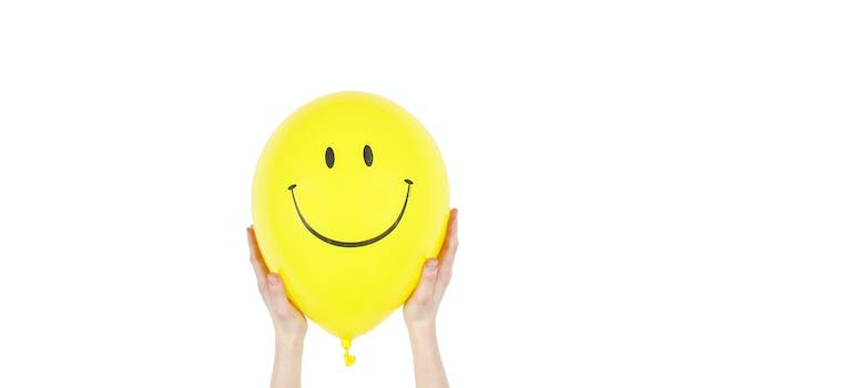 person holding a baloon with a smiley face