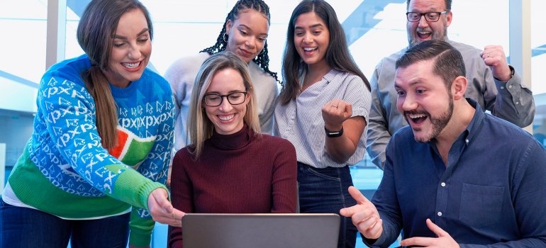 Men and women standing and sitting in the office to support and handle a coworker's drug or alcohol addiction. 