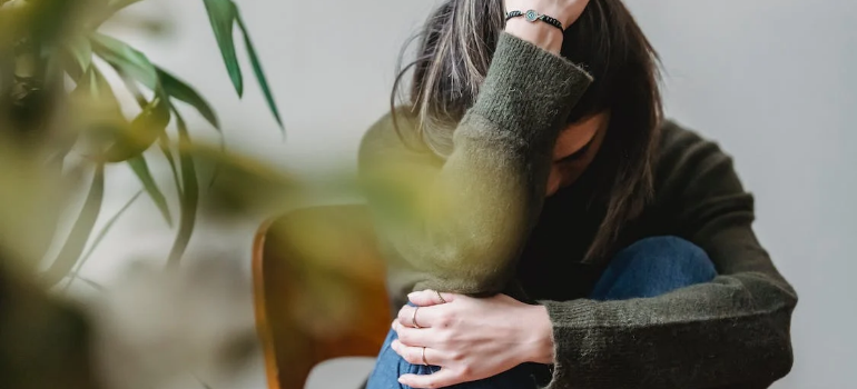a girl holding her head and thinking about her cocaine addiction in the PA workplace