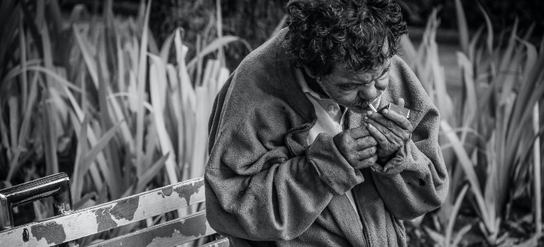 a black and white photo of a man smoking outside