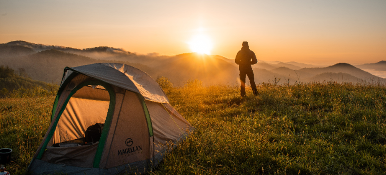 a man looking into the sun after stepping out of his tent during adventure therapy for substance abuse in Little Creek