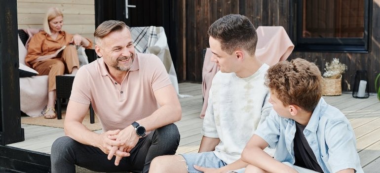 Father and sons are sitting on the stairs and talking.