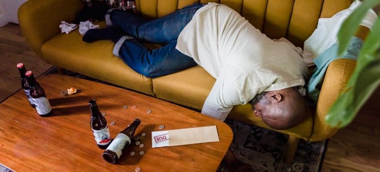 a drunk man in bed surrounded by bottles 