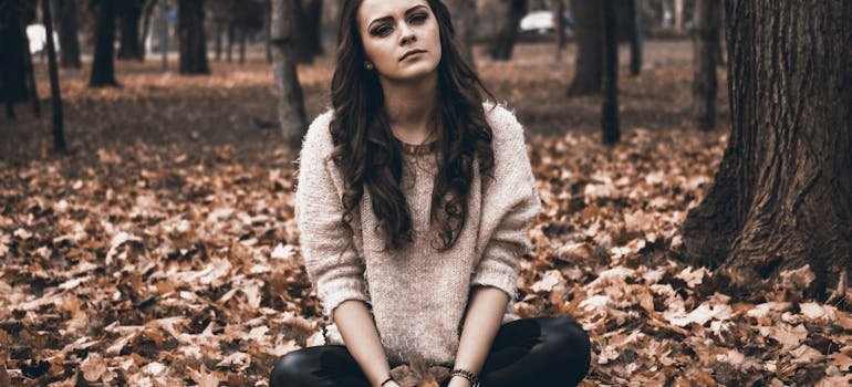 a sad woman sitting in the woods