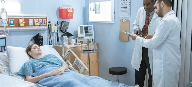 Doctors having a discussion while a patient lays in bed.
