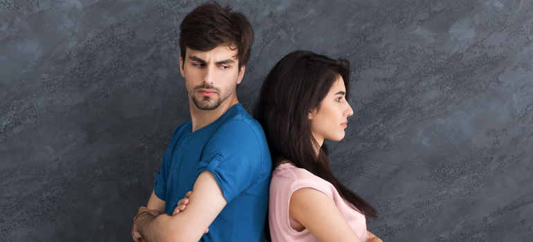 A straight couple back to back to each other looking distressed wondering can two addicts have a healthy relationship