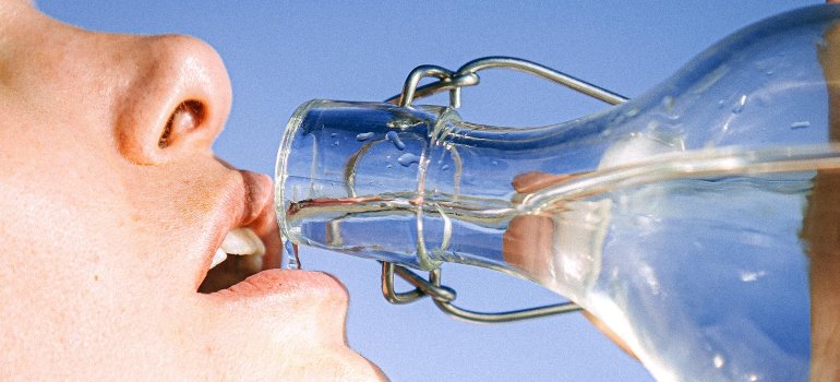 A person drinking water after mixing Dramamine and Alcohol