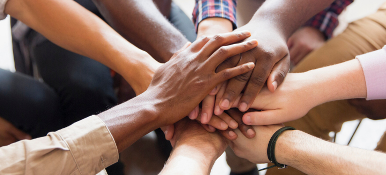 People putting their hands together expressing commitment to a common cause