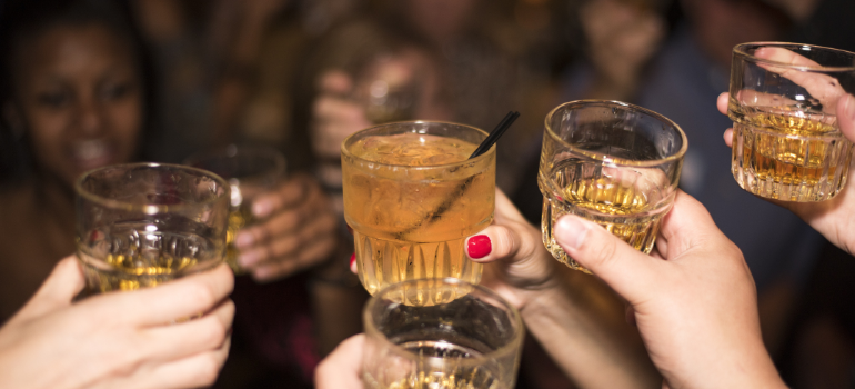 people at a party hold up full shot glasses