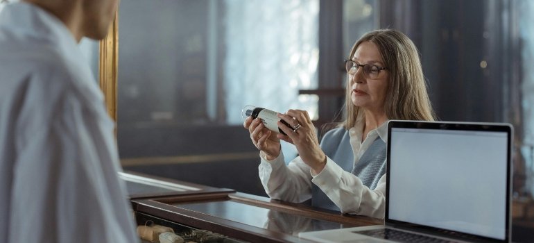 A woman holding a medicine bottle in a pharmacy