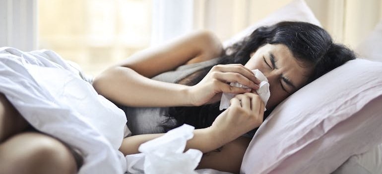 Woman lying in bed and blowing her nose.