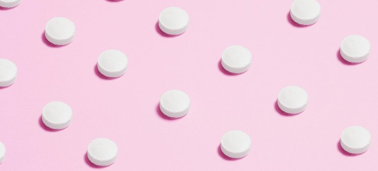 White pills on a pink background