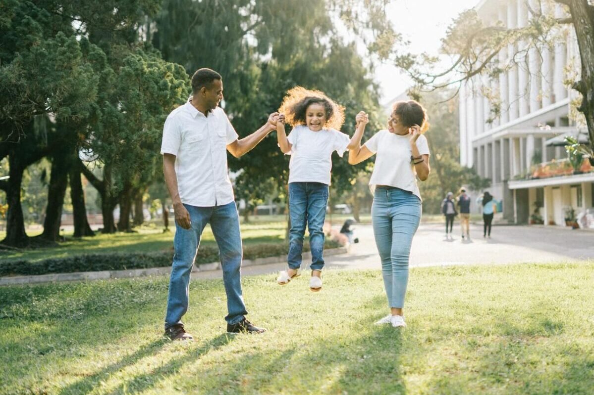 A family of three playing in a park
