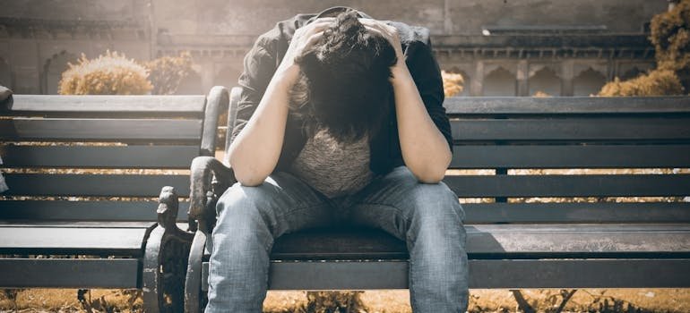 Man sitting on the bench and holding his head.