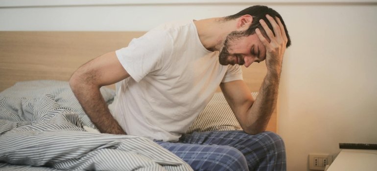 a man sitting on the bed, not feeling well 