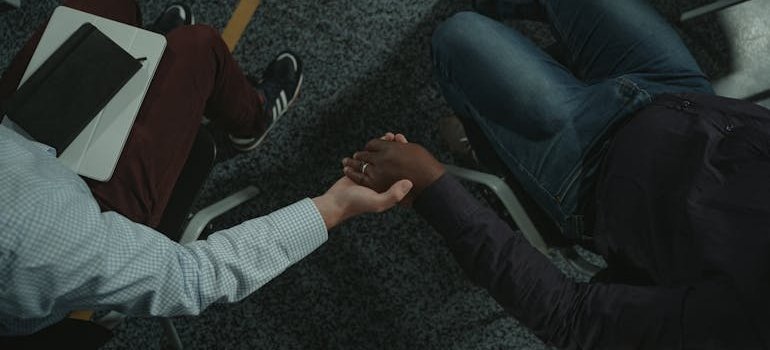 Two people in a support group holding hands.