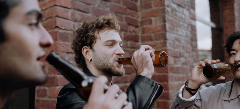 Three guys are drinking alcohol outside.