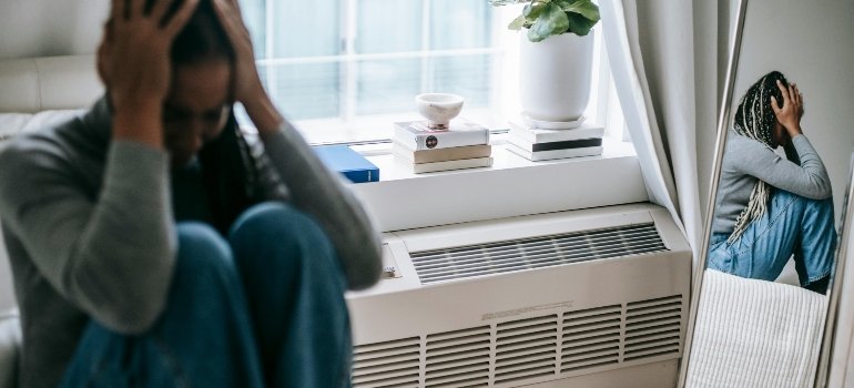 A depressed woman is holding her hands on her head and wondering "Do I have a drinking problem?"