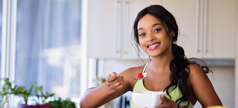 Woman laughing and eating a fruit bowl.