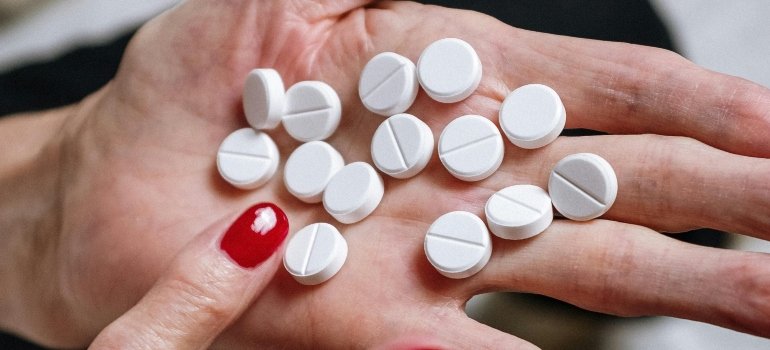 Woman counting pills on her hand.